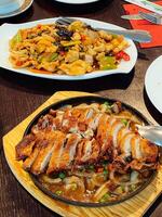 Sweet and sour chicken and Sichuan duck stand on plates on a table in a restaurant photo