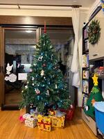 Multi-colored boxes with gifts lie near the decorated Christmas tree in the room photo