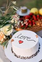 Wedding cake is on the table next to the bouquet of flowers. Caption. Love photo