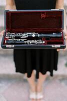chica-músico sostiene un clarinete en un caso en su manos. recortado sin rostro foto