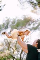 Dad throws a little girl up in his arms photo