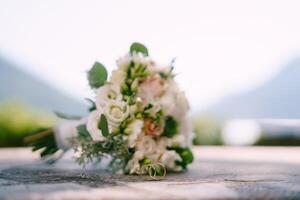 Pair of wedding rings stands against the background of the bridal bouquet photo