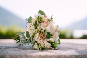 Crossed gold wedding rings stand against the background of the bride bouquet photo