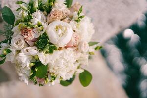 Luxurious bridal bouquet of peonies, roses and green branches. Top view photo
