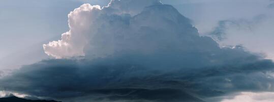 Thunderstorm cumulus clouds in sunbeams in blue sky photo