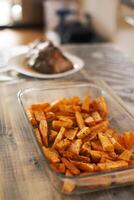 Sweet potatoes with rosemary in a glass bowl, standing on a wooden table photo