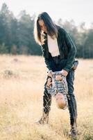 Smiling mother holding little laughing girl upside down while standing in the meadow photo