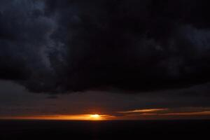 naranja racha de puesta de sol en un oscuro Tormentoso cielo foto