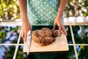 Housewife touches with her fingertips a cutting board with roast beef on the table photo