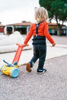 Little girl is pulling a toy cart with a soft toy inside. Back view photo