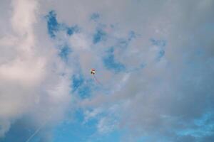 Colorful kite on a string soars in the cloudy sky photo