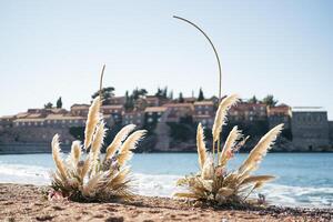 Wedding semi-arch stands on a sandy shore overlooking the island of Sveti Stefan. Montenegro photo