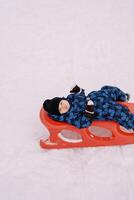 Little boy resting lying on a sled in the snow photo