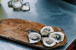 Halves of oysters lie on a wooden tray on the table photo