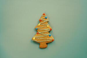 Christmas tree cookie with garlands painted with icing on a green background photo