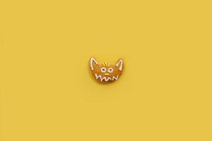 Funny glazed gingerbread cat lies on a yellow background photo