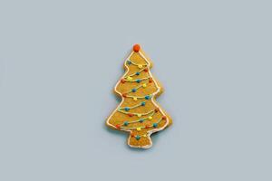 Christmas tree gingerbread cookie with colorful icing decorations on a blue background photo