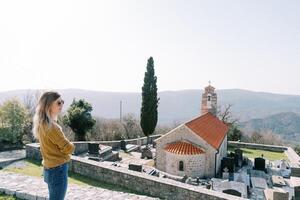 Young woman stands on an observation deck near the Church of St. Nicholas. Baosici, Montenegro photo