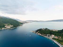 Resort town of Lepetane on the shore of the Bay of Kotor among green trees. Montenegro. Drone photo