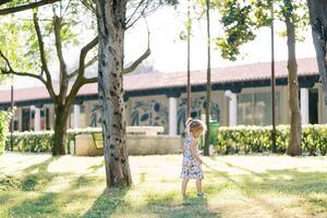 Little girl walks in a sunny park, looking at her feet. Side view photo