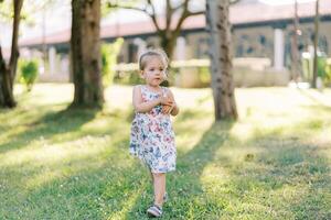 pequeño niña pensativamente caminando en un soleado parque foto