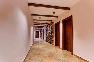 Long corridor of the hotel with colorful decorative panels and wooden doors of the rooms photo