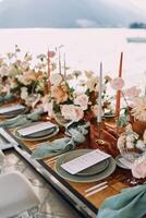Festive menus lie on plates near candles and bouquets of flowers on a wooden table photo