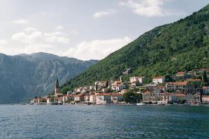 ver desde el mar de el costa de perast con antiguo casas y el alto campana torre de el iglesia. montenegro foto