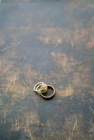 Wedding rings lie on a scratched painted table photo