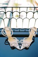 Wedding ring stands between the toes of shoes on a mirrored balcony table photo