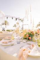 Festive table with candles in tall glass candlesticks against a blue sky photo