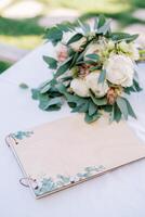 Guest memorial album lies on the table next to the bride bouquet photo