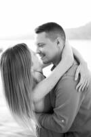 Man almost kisses woman bending her back by the sea. Black and white photo