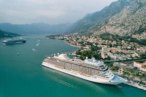 Huge cruise ships sail along the bay past the coast of the ancient town of Kotor. Montenegro. Drone photo