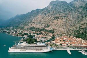 Cruise ship stands off the coast of Kotor with mountains in the background. Montenegro. Drone photo