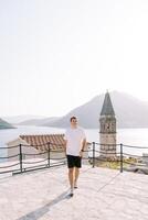Smiling guy walks along the observation deck near the church. Perast, Montenegro photo