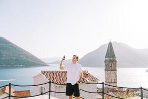 sonriente hombre toma un selfie en el plataforma con vista a el campana torre. peras, montenegro foto