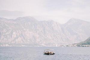 Excursion boat sails on the sea against the backdrop of a mountain range in a light haze photo