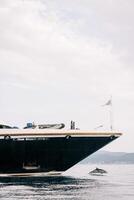 Dolphin swims in the sea near the bow of a ship against the backdrop of mountains photo