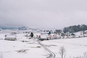 país la carretera en un pequeño cubierto de nieve pueblo en un montaña Valle foto