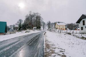 Ice-covered road in a village on the edge of a forest photo