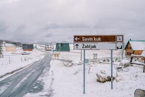 firmar cerca el la carretera a un Nevado pueblo en un montaña valle. subtítulo. salvando kuk, zabljak. montenegro foto