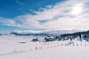 cubierto de nieve pueblo en un montaña Valle en brillante Brillo Solar foto