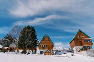 Mom with a small child sit on a sled near wooden cottages in the snow photo