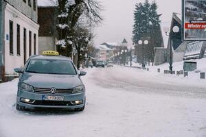 Taxi estacionado en el lado de un Nevado la carretera cerca un edificio foto