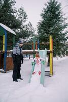 Mom looks at a little girl sliding down a snow-covered colorful slide photo