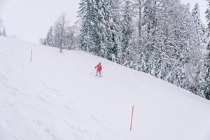 Skiers go down the ski slope with red posts photo