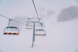 Quadruple chairlift rises above snowy forest to misty mountain photo