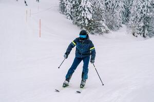 Skier in ski equipment rides, leaning to the side, on skis along a snowy track photo