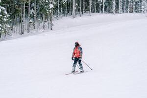 Skier in a red ski suit rides down the slope of a snowy mountain photo